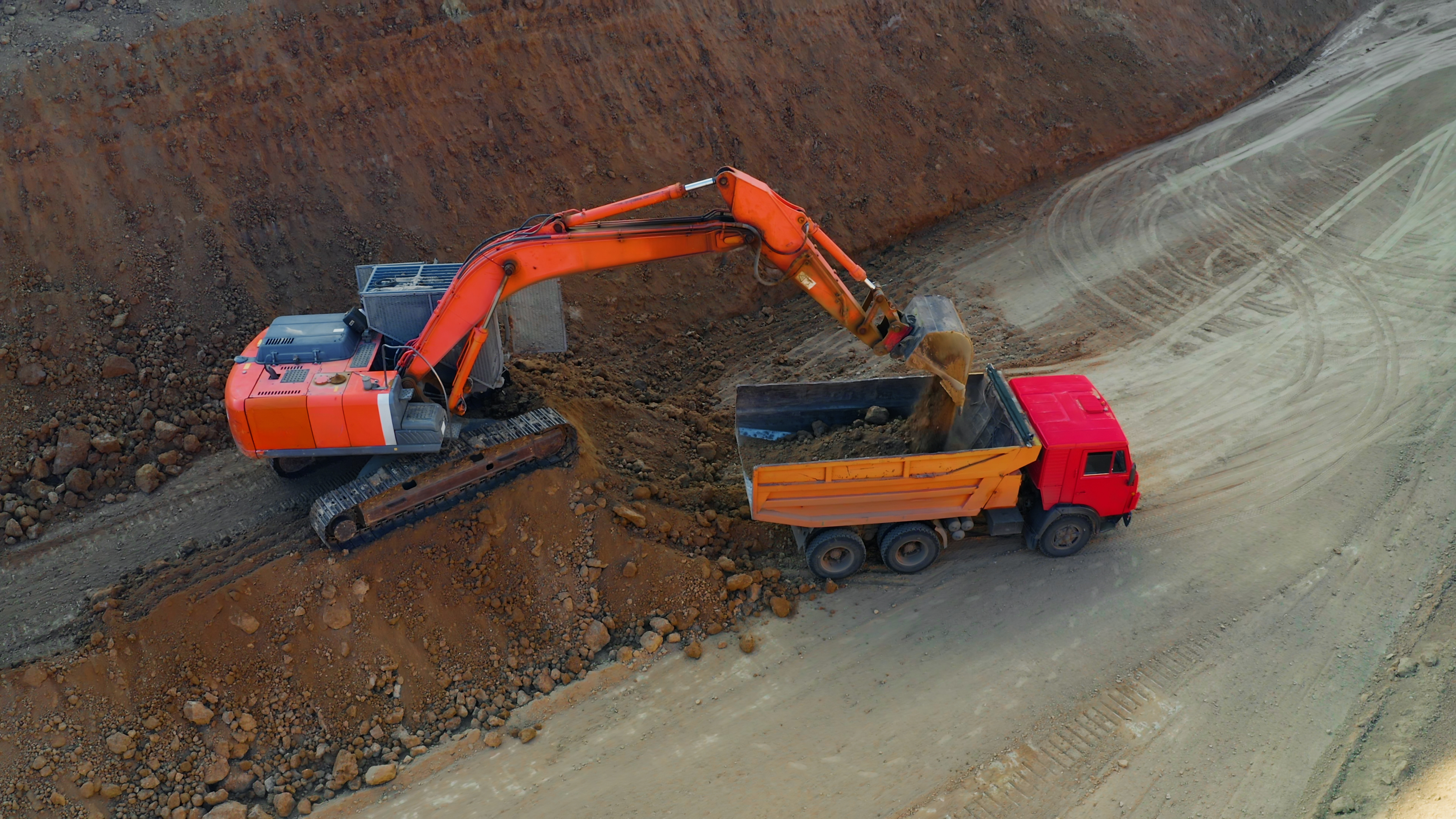 Excavadora naranja operando en un sitio minero a cielo abierto