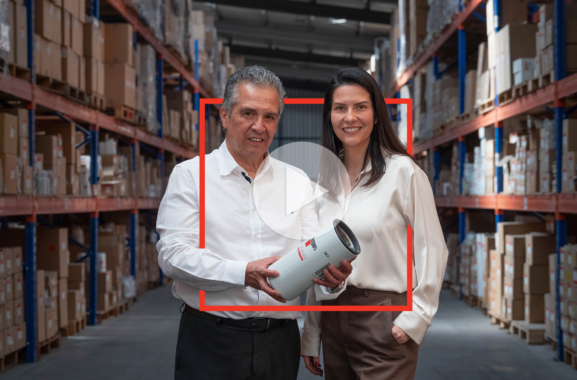two people in a warehouse holding a fleetguard filter